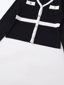 Detail of V-neck knit cardigan with gold buttons and contrast white trim details
