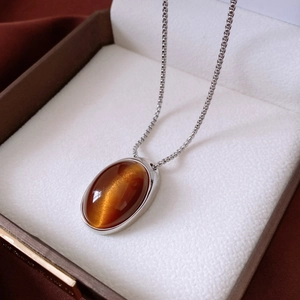 Detail of oval brown cat-eye resin pendant necklace displayed in a premium jewelry box
