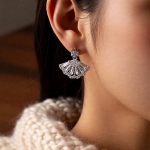 Macro shot of silver fan-shaped zircon earrings worn on ear for a luxury style