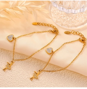 Close-up of gold titanium steel bracelet with diamond heart and ballerina pendant