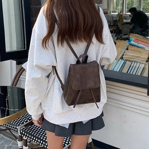 Primo piano di un piccolo zaino in pelle marrone vintage indossato da una modella all'aperto