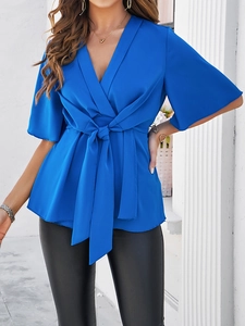 Détail du chemisier élégant en satin bleu avec col en V et ceinture à nouer à la taille