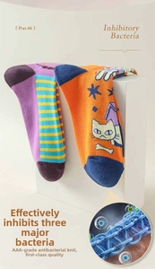 Close-up of asymmetric purple striped and orange cat pattern socks with AAA antibacterial label