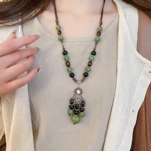Detailed close-up of a vintage ethnic necklace featuring green beads and metallic tassels