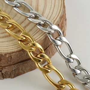 Detail of 18K gold and silver Figaro link necklaces on a rustic wood background
