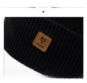 Detailed macro view of the black knit beanie fabric and brown leather logo patch