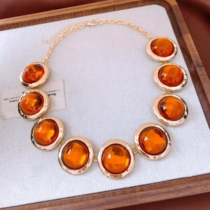 Dettaglio di collana vintage dorata con ciondoli in resina ambra su vassoio di lino