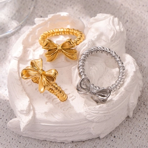 Tre anelli a fiocco in oro e argento con design a corda intrecciata su un piatto bianco
