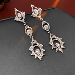 Macro detail of silver drop earrings with hollow rhombus and intricate crystals