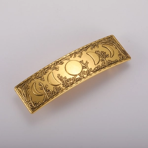 Detailed relief of moon phases and forest branches on a vintage gold alloy hair clip