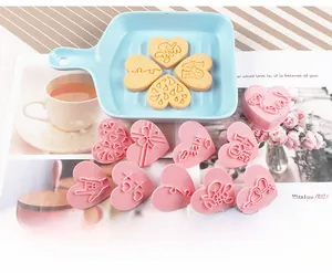 Pink heart-shaped 3D cookie cutters with LOVE and KISS patterns in a ceramic plate