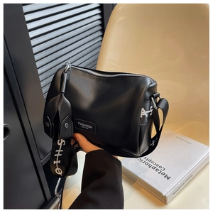 Détails du sac polochon en cuir noir texturé avec sa large bandoulière lettrée