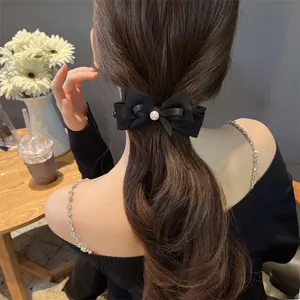 Detail view of a black vintage bow hair clip with white pearl on elegant long hair