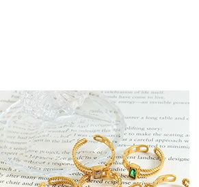 Macro detail of gold chain twist rings with emerald step-cut gemstones and sleek metal finish
