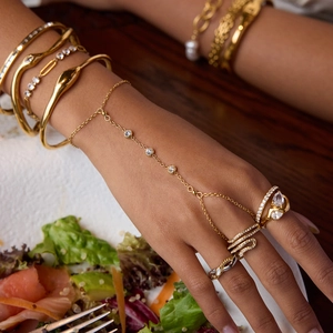 Elegante anello a serpente dorato e braccialetti con gemme indossati da una modella