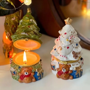 Detail of Christmas tree ceramic jewelry boxes with bear decor and lit candle inside