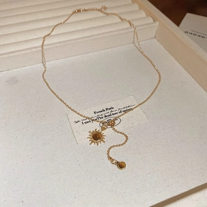 Macro detail of 18K gold plated necklace with sunburst pendant and brown tiger eye stone