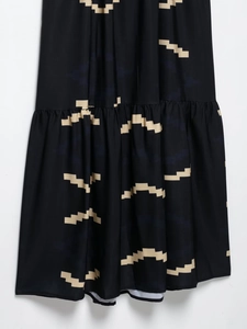Détail d'une robe fendue française noire avec imprimés géométriques et ourlet plissé