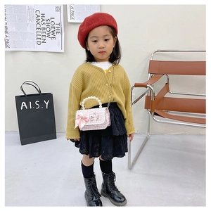 Pink tweed kids handbag featuring a satin bow, pearl handle, and golden chain strap
