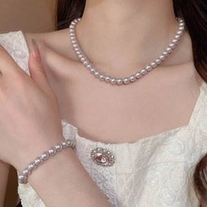 Close-up of French rose pearl necklace and bracelet set on a white lace dress