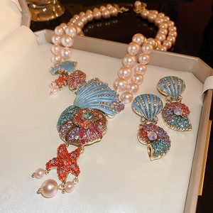 Close-up of double-layer pink pearl necklace with shell and starfish charms in box
