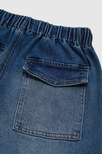 Detailed macro view of the elastic waistband and cargo pocket on high-density denim pants