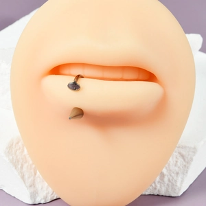 Macro view of silicone lip model showcasing metal piercing jewelry on textured stone