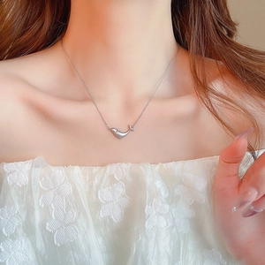 Elegant silver dolphin pendant necklace worn by a model in a warm interior setting