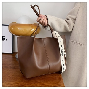 Detail of a brown leather tote bag with elegant silk ribbon and fine stitching texture