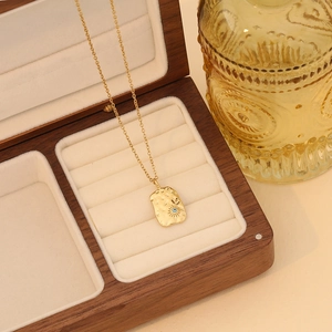 Detailed close-up of a gold heart necklace with evil eye and star on a walnut box