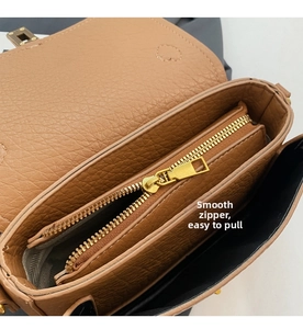 Detail of the smooth golden metal zipper and black inner lining of the brown handbag