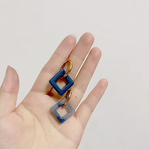 Detailed shot of vintage gold earrings with blue marbled square resin pendants