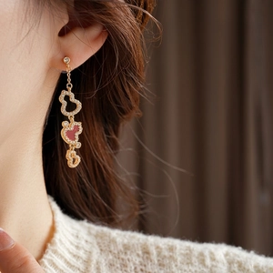Gold-plated gourd tassel earrings with red enamel and pavé crystals on a model