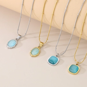 Detailed view of gold and silver necklaces with cat eye stone pendants on a beige steps