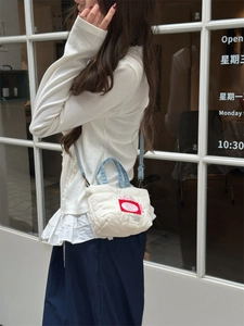 Mini borsa a tracolla trapuntata bianca con manici in denim blu indossata da modella