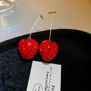 Boucles d'oreilles fraises en cristal étincelant avec feuilles dorées sur plateau velours