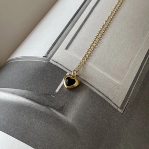 925 silver black onyx heart necklace with gold frame on architectural magazine backdrop