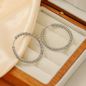 Close-up of silver twisted rope hoop earrings resting in a premium wooden jewelry box