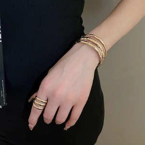 Detailed view of golden bamboo textured cuff bracelet and matching ring on model wrist