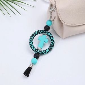 Detail of blue silicone cross keychain with leopard print ring and black tassel on bag