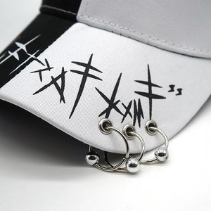 Detail of baseball cap brim featuring black graffiti print and silver metal rings