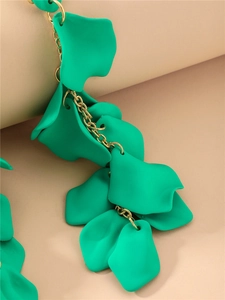 Détail de boucles d'oreilles pendantes élégantes avec pétales verts et chaînes dorées