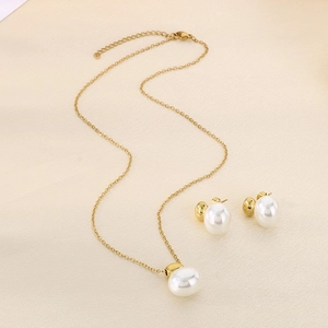 Detailed view of golden necklace and matching pearl stud earrings on textured fabric