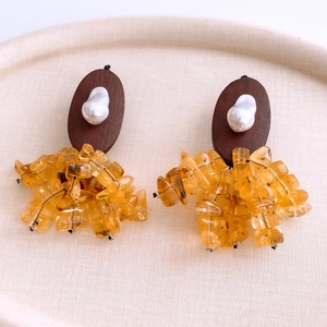 Close-up of vintage resin earrings with oval wood base, white pearl and yellow stones