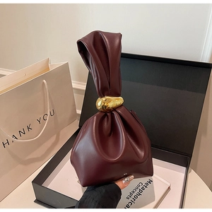 Detail of burgundy leather pleated bucket bag with gold metal ring in premium gift packaging
