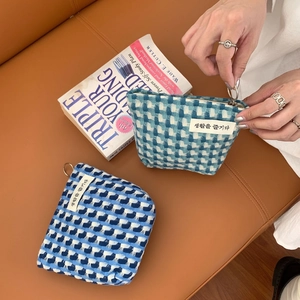 Détail de la trousse tissée à damier bleu avec fermeture éclair et étiquette textile