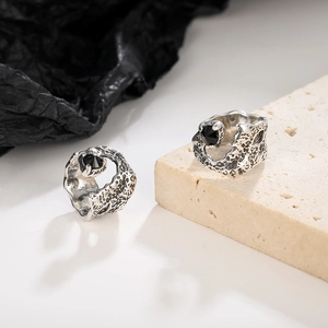 Retro silver ear cuff with black zircon and vintage lava texture on a stone base