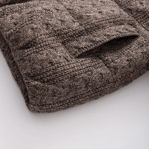 Detailed close-up of chunky cable knit texture and side pocket on grey knitted cardigan