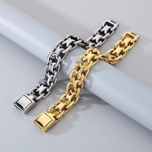 Close-up of interlocking silver and gold stainless steel link bracelets on grey pedestal