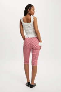 Rear view of model wearing red and white plaid cropped pants and white ruffled top